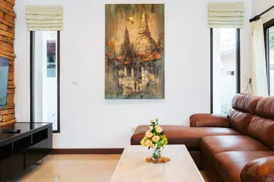 a living room with a couch and a painting on the wall at San pool villa in Patong Beach