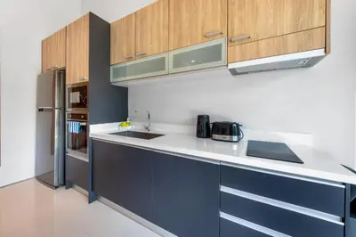 a kitchen with wooden cabinets and a white counter top at \u5bbd\u655e\u8212\u9002 \u90a6\u6d9b\u6d77\u6ee9Laguna\u9644\u8fd1 \u56db\u5367\u5ba4\u79c1\u4eba\u6cf3\u6c60\u522b\u5885 V07 in Phuket Town