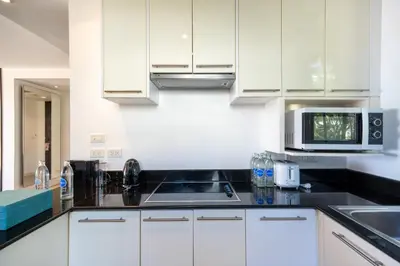 a kitchen with white cabinets and a microwave at Karon Beachfront Apartment 703 in Karon Beach