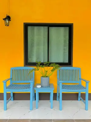 two blue benches and a table in front of an orange wall at Cuckoo's Nest Ao Nang in Ban Khlong Son