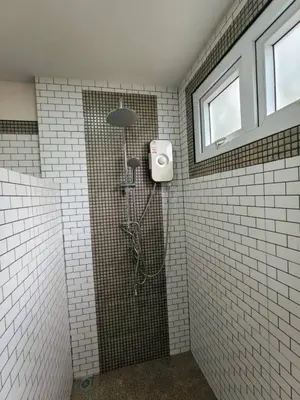 a shower in a bathroom with white tiles at Picha house Kohyaonoi in Ban Laem Sai