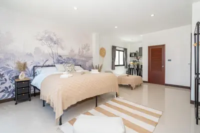 a bedroom with two beds and a painting on the wall at Mitsu Guesthouse in Karon Beach