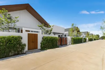 a white house with a gate and a driveway at The Ozon Bangtao 3-bedrooms Villas with pool by My Home Phuket in Laguna Phuket