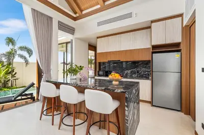 a kitchen with a island with bar stools at The Ozon Bangtao 3-bedrooms Villas with pool by My Home Phuket in Laguna Phuket