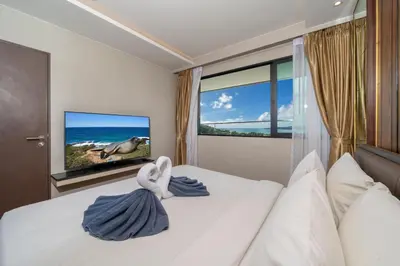 a bedroom with a bed with a tv and a window at Surin sea view 3br apartment with jacuzzi in Surin Beach
