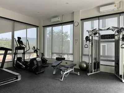 a gym with treadmills and exercise equipment and windows at Title Halo Timeless Naiyang Pool Gym Sauna in Nai Yang Beach