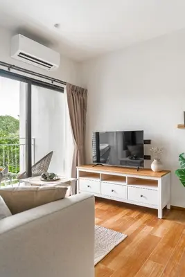 a living room with a couch and a tv at Title Halo Timeless Naiyang Pool Gym Sauna in Nai Yang Beach