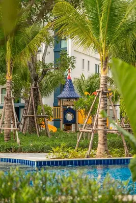 a playground with a clock and palm trees in front of a building at Title Halo Timeless Naiyang Pool Gym Sauna in Nai Yang Beach