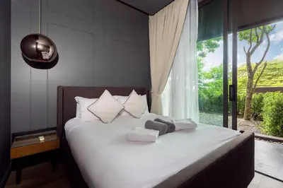 a bedroom with a white bed with a large window at Spacious Pool Access Apartment with 2 BR - Rawai in Ban Saiyuan (1)