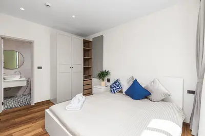 a white bedroom with a bed and a sink at The Title Halo NaiYang by My Home Phuket in Nai Yang Beach