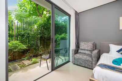 a bedroom with a bed and a chair and a window at Studio Apartment - Emerald Terrace Patong in Patong Beach