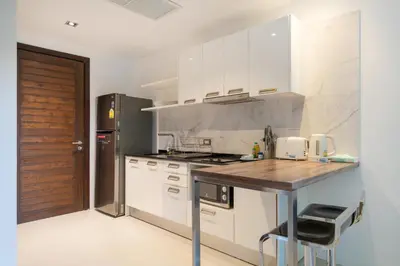 a kitchen with white cabinets and a wooden counter top at Studio Apartment - Emerald Terrace Patong in Patong Beach