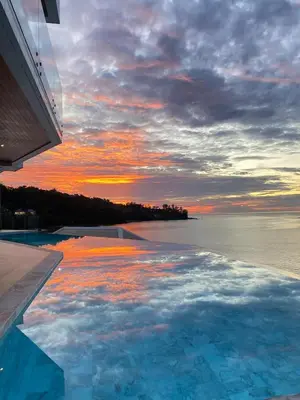 a swimming pool with a view of the ocean at sunset at Cape Sienna Villa 4-Oceanfront 5-Bedroom Luxury Villa with 22 m Infinity Pool in Kamala Beach