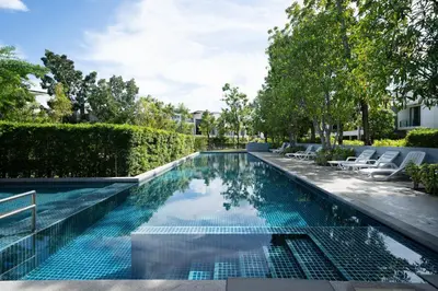 an infinity pool with chairs and trees at Laguna pool house in Phuket Town