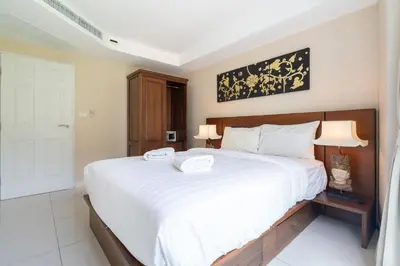 a bedroom with a large white bed with two towels on it at Mountain View Apt, High Speed Internet - 1BR-Karon in Kata Beach