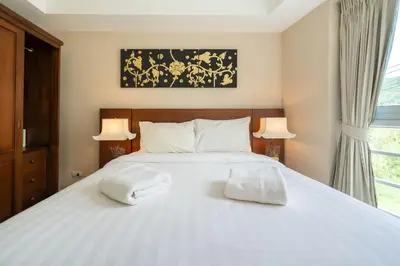 a bedroom with a white bed with two towels on it at Mountain View Apt, High Speed Internet - 1BR-Karon in Kata Beach