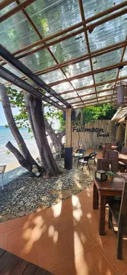 a patio with a table and chairs and a tree at Fullmoon Beachresort Krabi in Ao Nang Beach