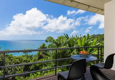a balcony with a table and chairs and the ocean at Villa Yin, Private Oceanfront Villa, Kamala Beach in Kamala Beach