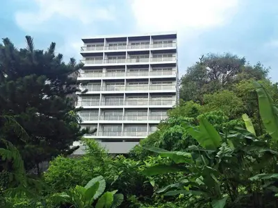 a tall building with trees in front of it at Ocean View Treasure Residence in Patong Beach