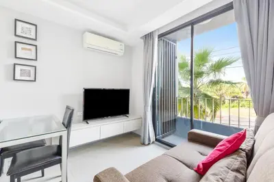 a living room with a couch and a tv and a window at 6th Avenue Surin Condomium in Surin Beach