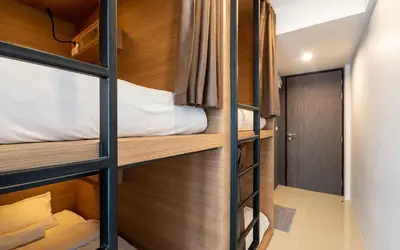 two bunk beds in a room with a door at Kata Beach Poshtel Phuket in Kata Beach