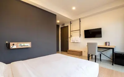 a bedroom with a bed and a desk with a television at Kata Beach Poshtel Phuket in Kata Beach