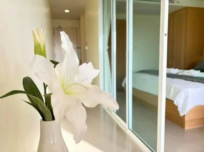 a white vase with a white flower in a room at มัณดาวีต์ คอนโดa in Ban Khlong Son
