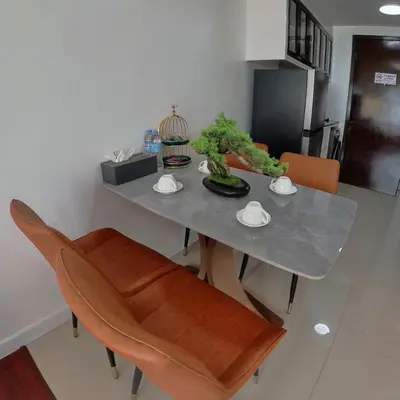 a dining room table with chairs and a table with a plant on it at The Kris Cozy 2-Bedrooms Apartment in Patong Beach