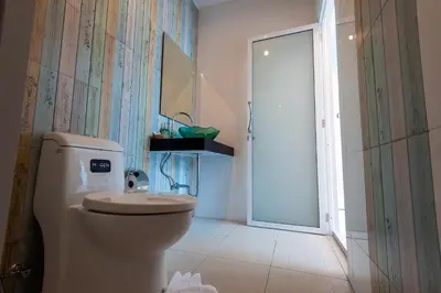 a bathroom with a toilet and a sink and a door at Jinda Resort in Nai Yang Beach
