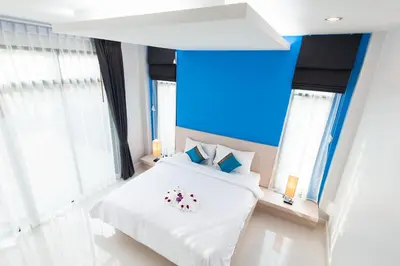 a bedroom with a white bed and windows at Jinda Resort in Nai Yang Beach