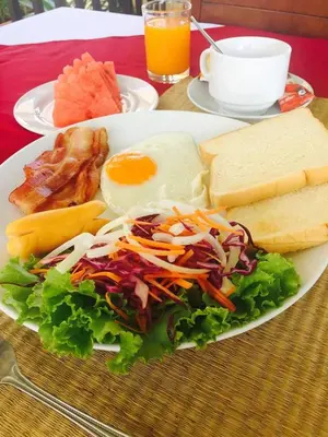 a plate of food with an egg and a salad at Jinda Resort in Nai Yang Beach
