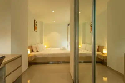 a bedroom with two beds and a glass wall at Cozy 1BR Poolside Apartment with Scenic Balcony C132 in Surin Beach