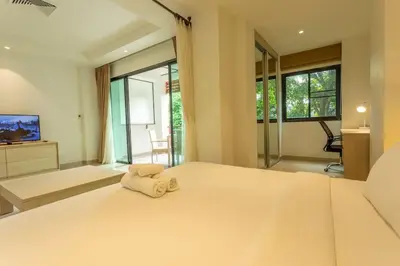 a large bedroom with a bed with a towel on it at Cozy 1BR Poolside Apartment with Scenic Balcony C132 in Surin Beach