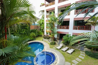 a hotel with a swimming pool in front of a building at Cozy 1BR Poolside Apartment with Scenic Balcony C132 in Surin Beach