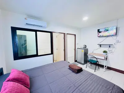 a bedroom with a large bed and a desk at KLApartment in Ban Bang Chak