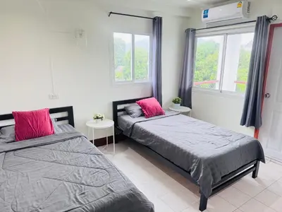 two beds in a room with two windows at KLApartment in Ban Bang Chak