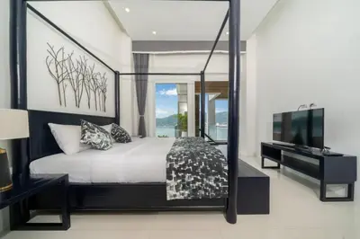 a bedroom with a large bed and a television at Patong WiN HOUSE Villa in Patong Beach