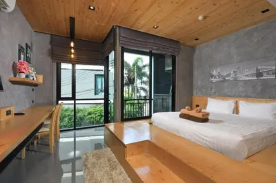 a bedroom with a large bed and a desk andwindows at Relife Windy B226 at NaiHarn beach by CapitalPro in Phuket Town