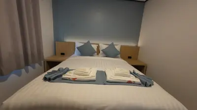 a bedroom with a white bed with blue pillows at Jong's House- Phi Phi Island in Phi Phi Don