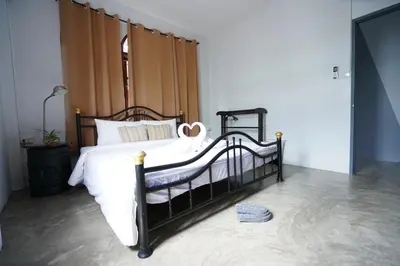 a bedroom with a black bed with white sheets at Amahostel in Ban Thalat Choeng Thale
