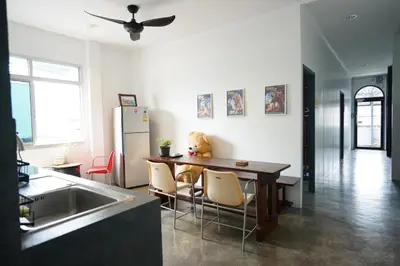 a kitchen with a table and a refrigerator at Amahostel in Ban Thalat Choeng Thale