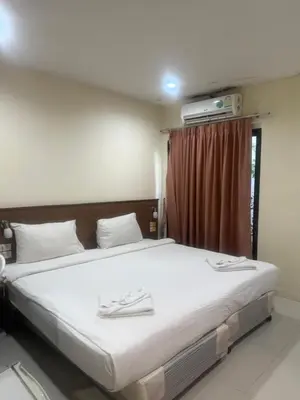a bedroom with a bed with white sheets and a window at Royal Waves Hotel in Patong Beach
