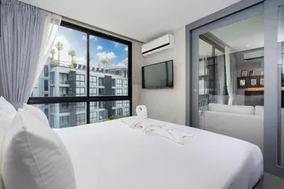 a bedroom with a white bed and a large window at Your Relaxing Stay! Suite CTG P506 at Tropics Kamala Residence with Scenic Rooftop Pool and Great Amenities in Kamala Beach
