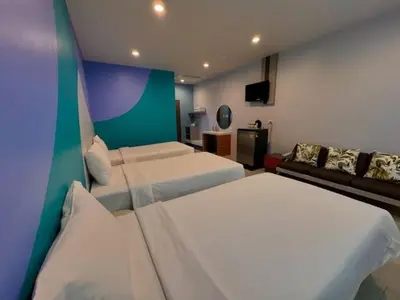 a hotel room with two beds and a couch at Siri Hotel Phuket in Phuket Town