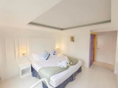 a white room with a bed and a chair at Chilli Salza Patong in Patong Beach