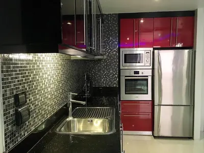 a kitchen with a stainless steel sink and red cabinets at Absolute bangla suites 65 sqm with Jacuzzi in Patong Beach