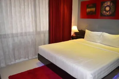 a bedroom with a white bed and a red curtain at Absolute bangla suites 65 sqm with Jacuzzi in Patong Beach