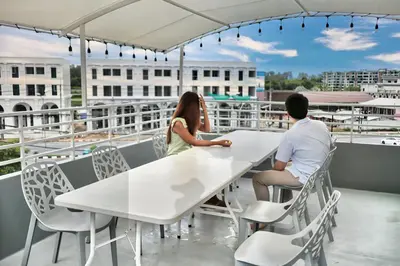 a man and a woman sitting at a table on a balcony at Friends Hostel - Phuket Airport in Nai Yang Beach