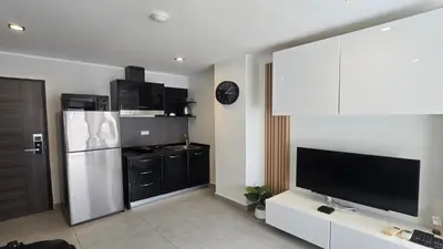 a living room with a television and a refrigerator at Island Escape 1BR T1-206 in Chalong