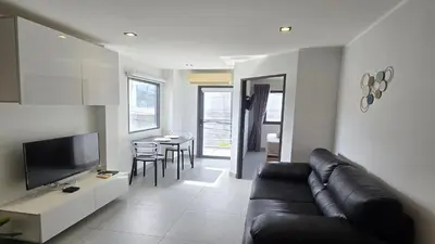 a living room with a black leather couch and a television at Island Escape 1BR T1-206 in Chalong